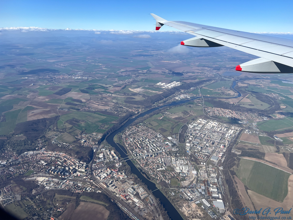 An aerial view with a river and buildings below. You can see the aircraft wing also