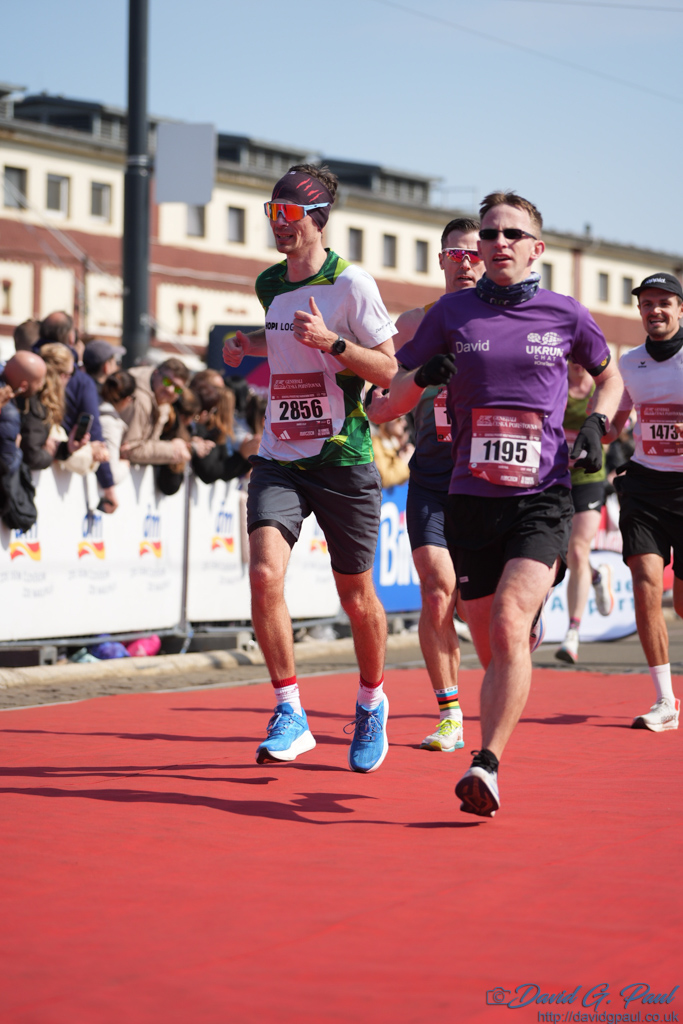 Runners running along a red carpet with spectators to one side