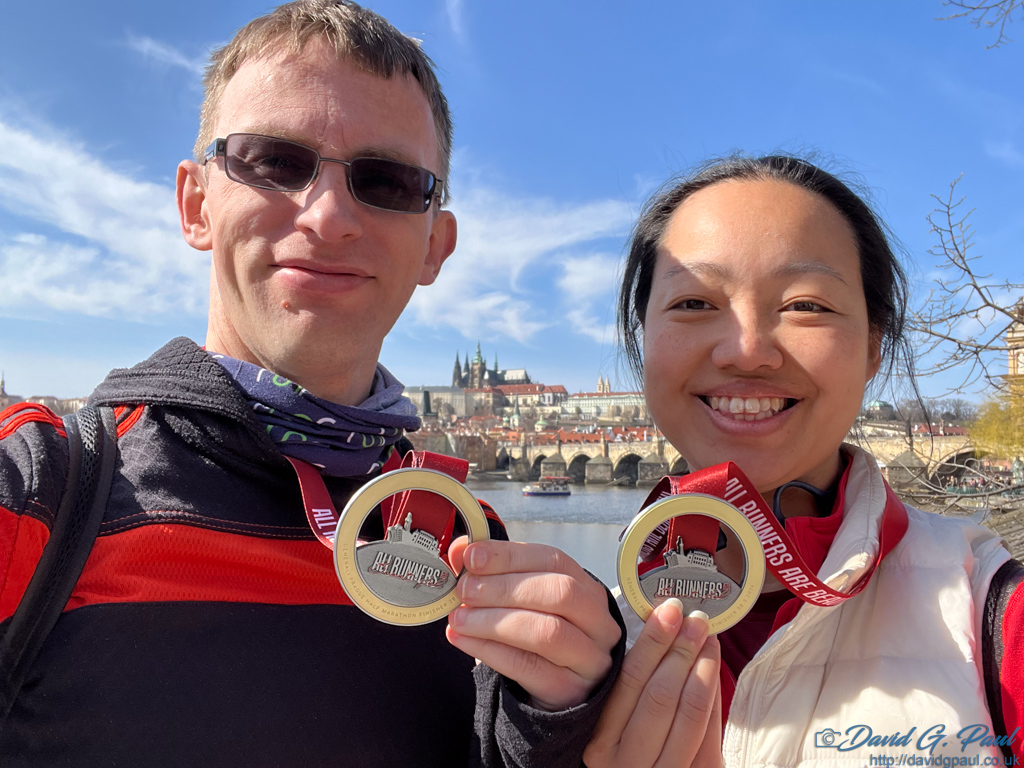 A male and female holding up medals to the camera; both are dressed in warm clothes