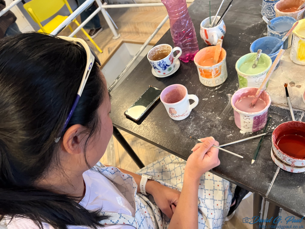Looking down at a woman painting a mug