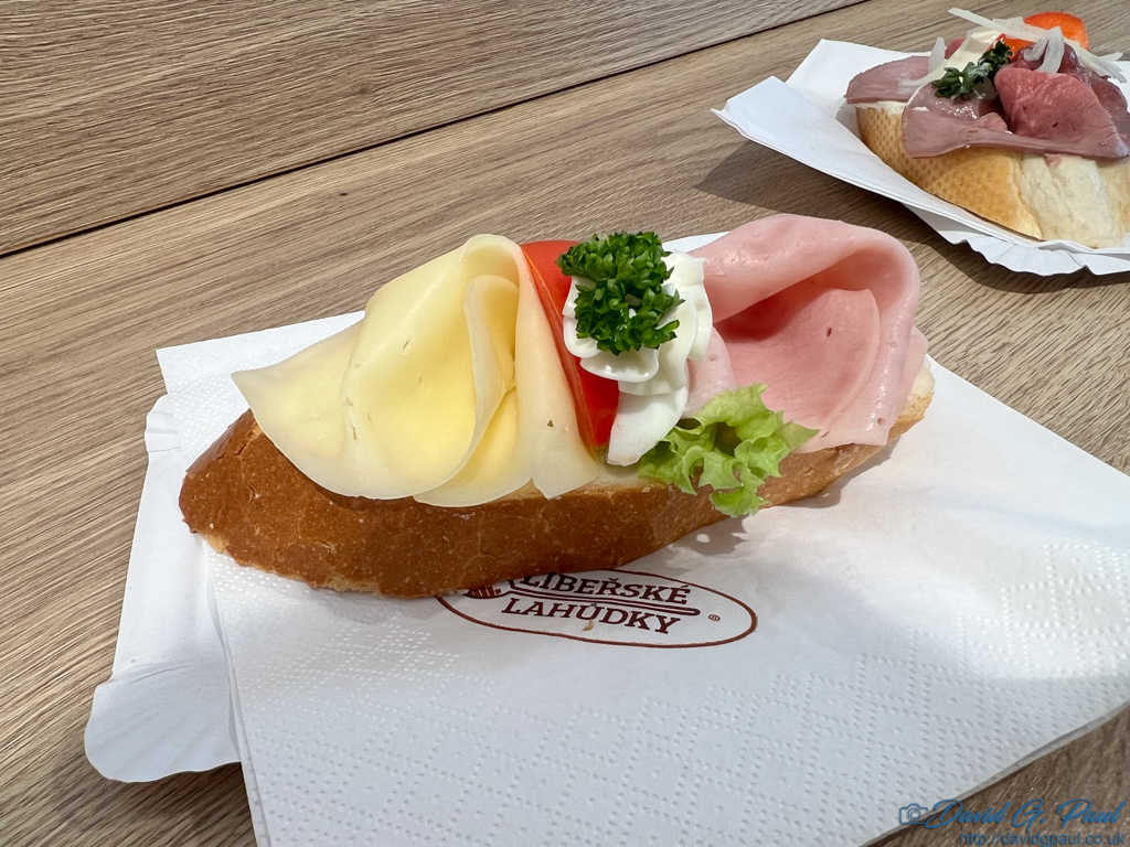 A slice of baguette with cheese, ham, and tomato