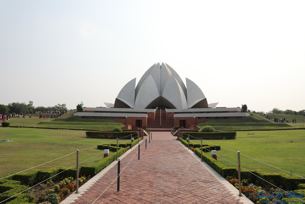 A red path leading towards a white building shaped like a lotus flower