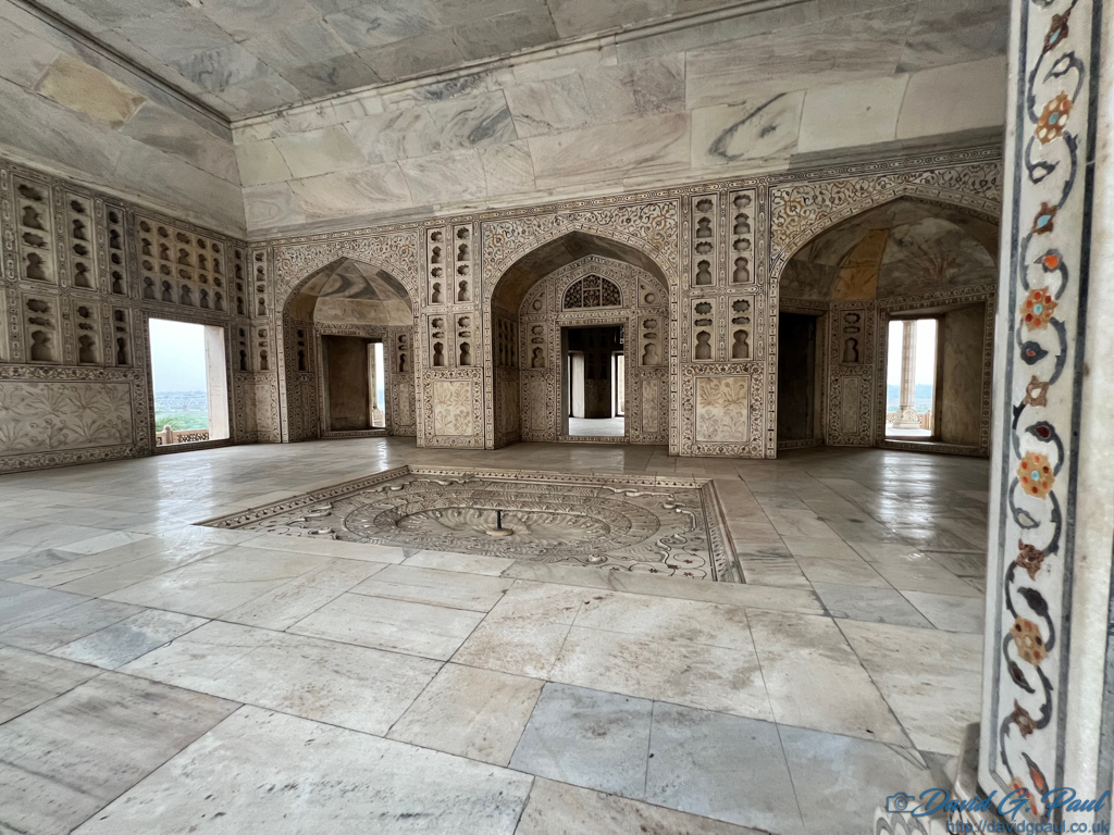 A room made entirely of marble, with small mirrors on walls, and inlaid precious stones in floral patterns