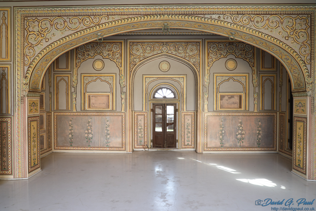 Detailed paintings on walls with an archway, and a door.