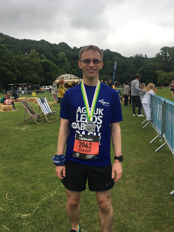 A male wearing running clothes and wearing a finishers medal from a running race.