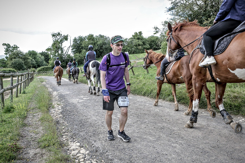 A male runner walking amongst people on horseback