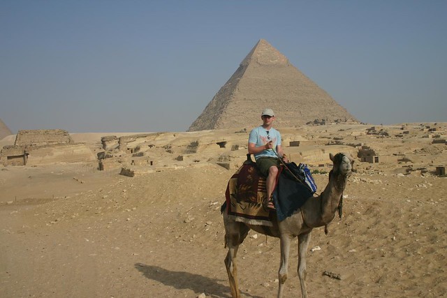 Riding a camel passed the pyramids