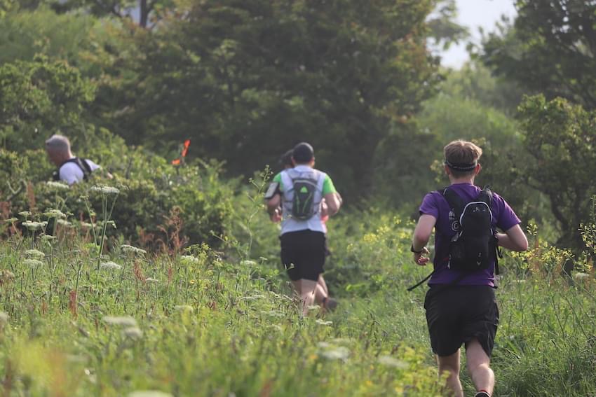 People running through tall grass