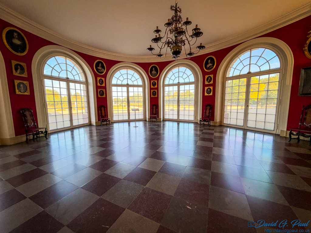 Four full-height windows on a curved wall shine light onto the polished checkerboard floor.